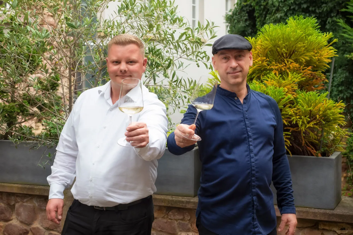 Christian Rubert und René Fischer im Garten des Halbstücks mit Weingläsern