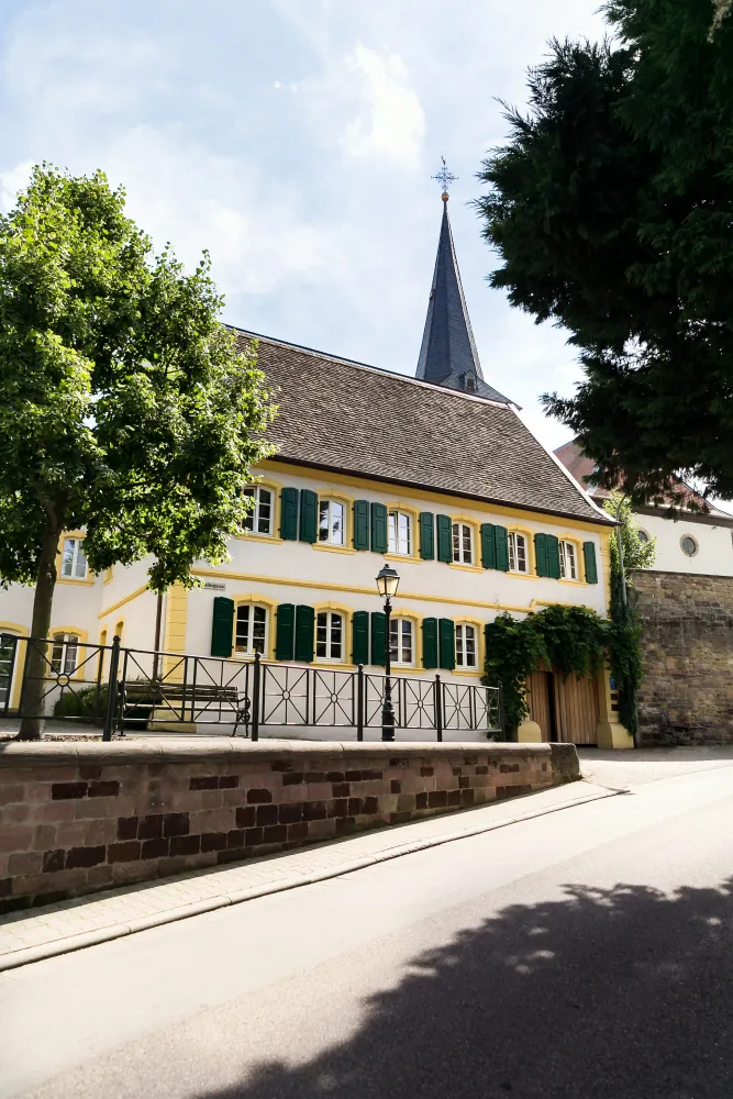 Fassade des Halbstücks mit dem Kirchturm dahinter