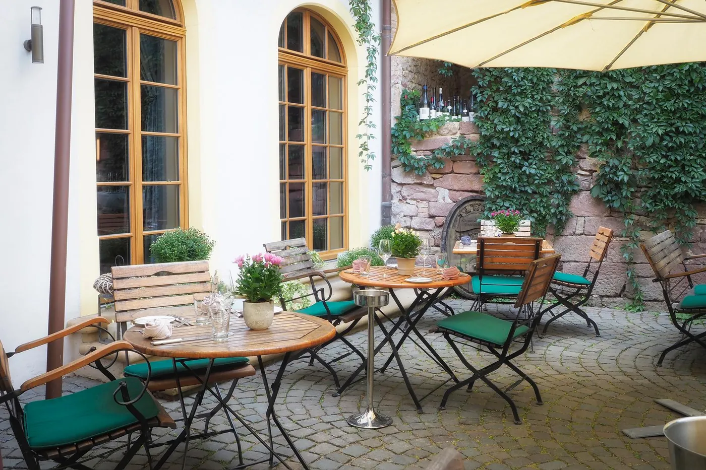 Gedeckte Tische im efeuberankten Innenhof des Halbstücks
