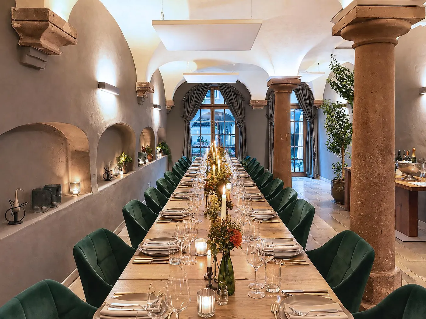 Kreuzgewölbe mit Säulen und langer Tafel bei Kerzenlicht