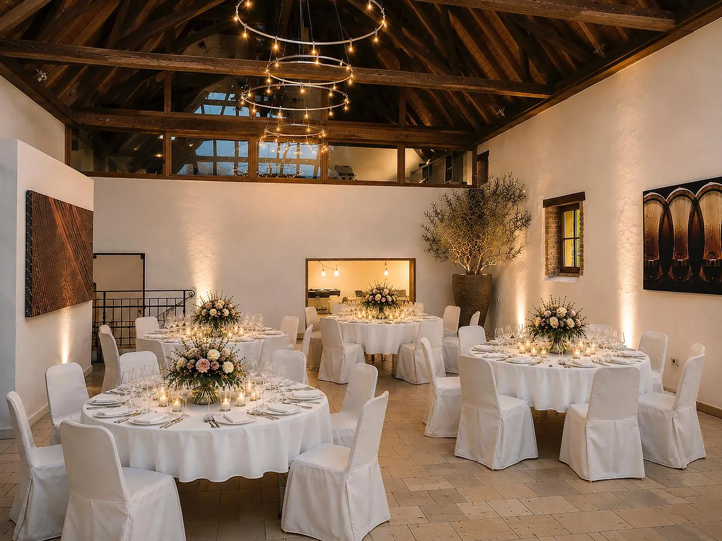 Scheune mit runden Hochzeitstischen, Blumen und Kronleuchtern